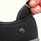 Two fingers holding heel tab on Black Men's Extra Wide Comfort Shoes on a white background