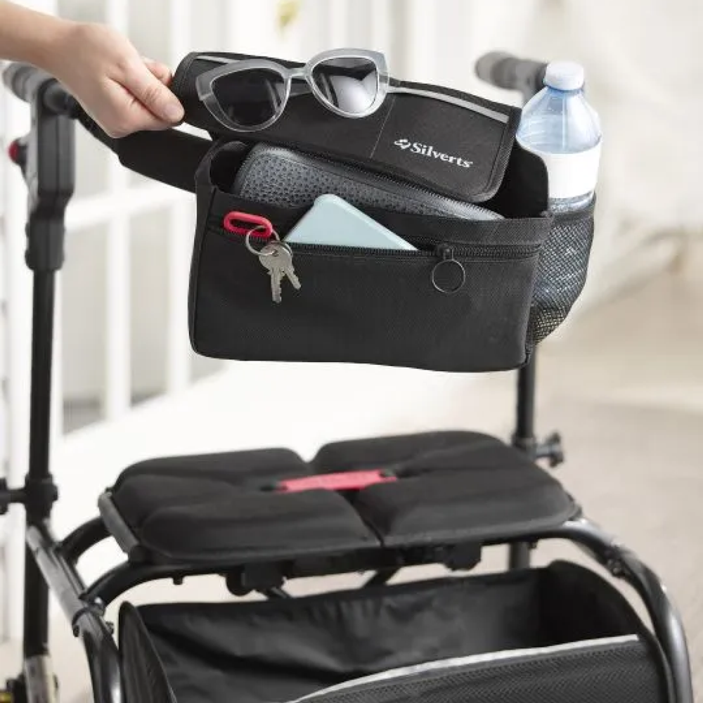 Silverts Wheelchair Walker Utility Bag in Black displayed in use on a wheelchair with a wallet, phone, key ring, bottle of water, and pair of sunglasses.