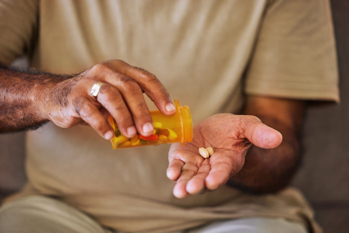 A person putting pills in their hand.