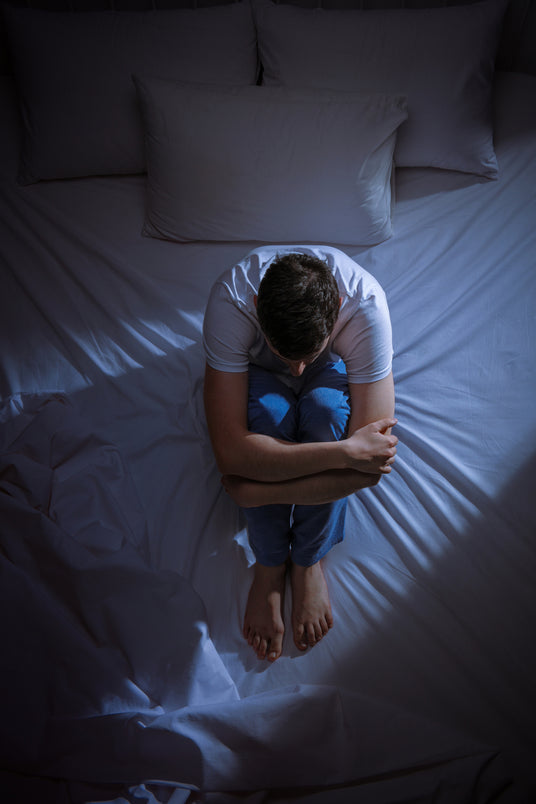 A man sits on his bed at night