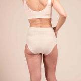 Beige background with a woman facing backward wearing beige underwear