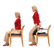 Woman wearing a red sweater and khaki pants displaying how to use the cushion set and how to get it from cushion on seat. 