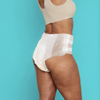 Back view of woman wearing Because Maximum tabbed briefs on teal background
