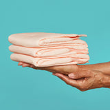 A pile of folded bed protectors in a woman's hands