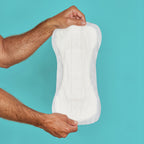 Two hands showing how a booster pad looks on teal background