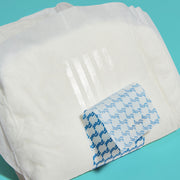 The back of a booster pad with the removable adhesive strip being peeled off