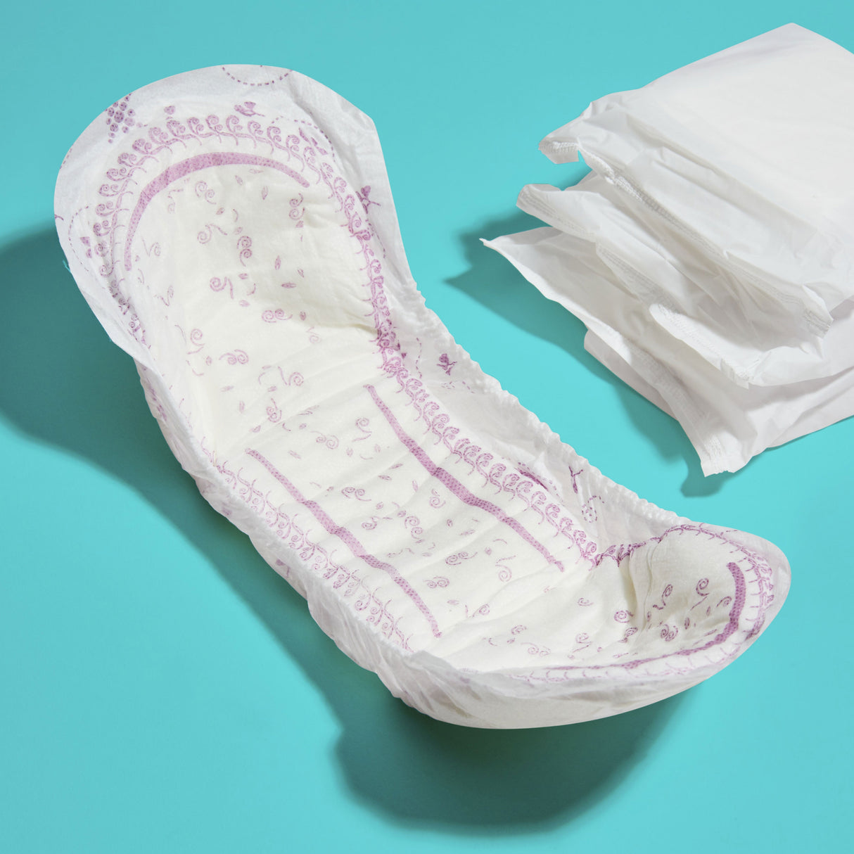 A curved pad that looks absorbent and comfortable next to three individually wrapped pads 