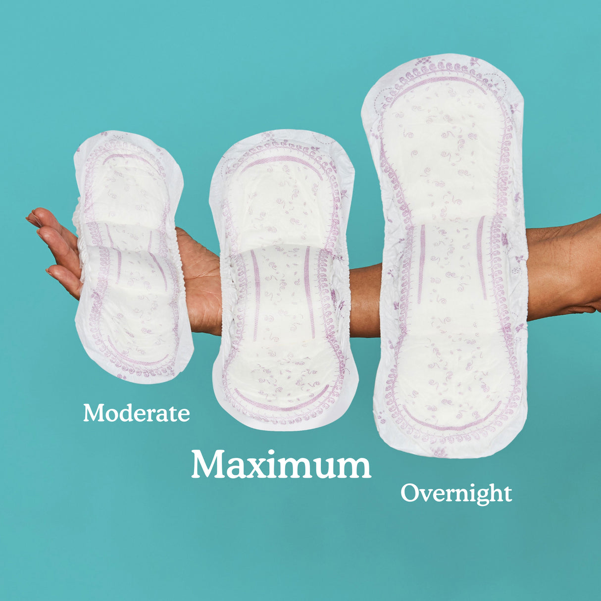 Woman holding 3 sizes of pads in her arm with maximum being the absorbency between moderate and overnight