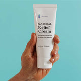 Hand holding a tube of natural relief cream