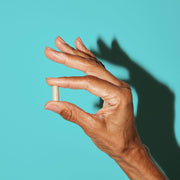 Woman holding one capsule between her fingers